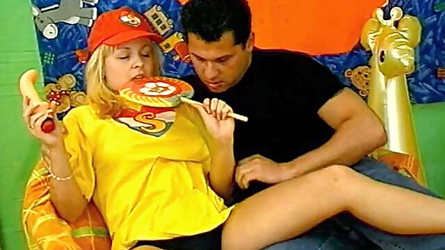 A hot blonde in a t-shirt fucks a guy while sucking her toy